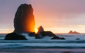 Preview wallpaper ocean, rock, sunset, rays, surf