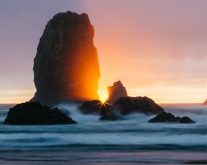 Preview wallpaper ocean, rock, sunset, rays, surf