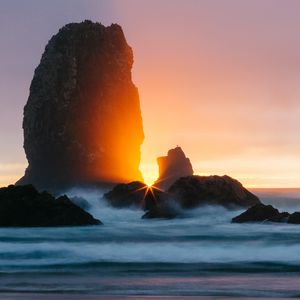 Preview wallpaper ocean, rock, sunset, rays, surf