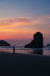 Preview wallpaper ocean, silhouette, sunset, rocks, loneliness