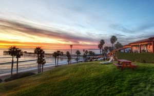 Preview wallpaper palm trees, coast, sea, table, benches, picnic, slope, evening