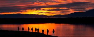 Preview wallpaper people, silhouettes, sunset, lake, mountains