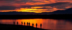 Preview wallpaper people, silhouettes, sunset, lake, mountains
