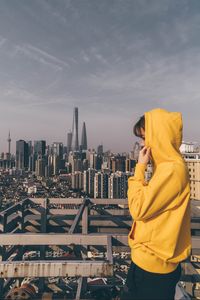 Preview wallpaper person, hoodie, yellow, city, buildings