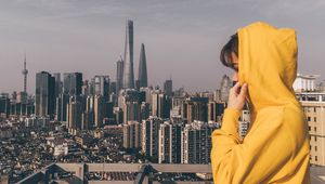 Preview wallpaper person, hoodie, yellow, city, buildings