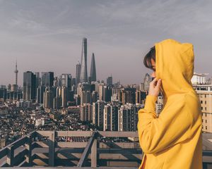 Preview wallpaper person, hoodie, yellow, city, buildings