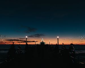 Preview wallpaper pier, dark, garlands, lights, silhouettes