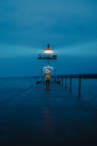 Preview wallpaper pier, man, lighthouse, umbrella, sea, twilight