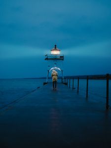 Preview wallpaper pier, man, lighthouse, umbrella, sea, twilight