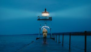 Preview wallpaper pier, man, lighthouse, umbrella, sea, twilight