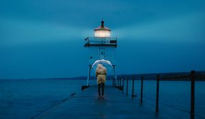 Preview wallpaper pier, man, lighthouse, umbrella, sea, twilight