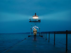 Preview wallpaper pier, man, lighthouse, umbrella, sea, twilight