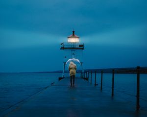 Preview wallpaper pier, man, lighthouse, umbrella, sea, twilight