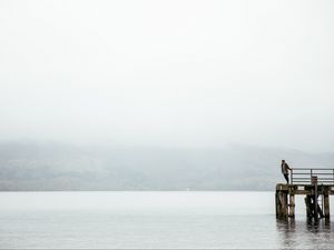 Preview wallpaper pier, man, loneliness, melancholia, lake, fog, water