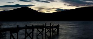 Preview wallpaper pier, mountains, silhouette, sunset