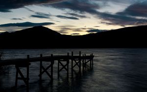 Preview wallpaper pier, mountains, silhouette, sunset