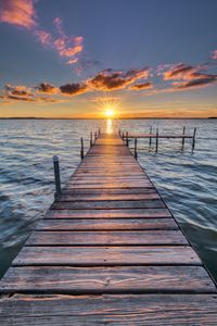 Preview wallpaper pier, sunset, rays, horizon, sea