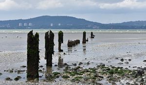 Preview wallpaper pilings, shore, pebbles, sea, mountains
