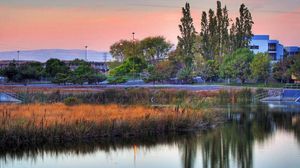 Preview wallpaper river, buildings, sunset, sky, grass, trees