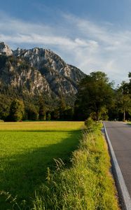 Preview wallpaper road, asphalt, field, green, trees, mountains, castle