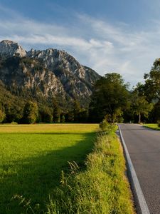 Preview wallpaper road, asphalt, field, green, trees, mountains, castle