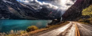 Preview wallpaper road, asphalt, sun, light, patches of light, midday, river, coast, marking, lines, double continuous, paint, clouds, volume