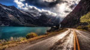 Preview wallpaper road, asphalt, sun, light, patches of light, midday, river, coast, marking, lines, double continuous, paint, clouds, volume