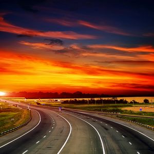 Preview wallpaper road, decline, asphalt, turn, signs, sky, orange, evening