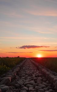 Preview wallpaper road, distance, sunset, stones, grass