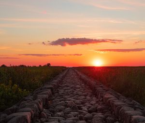 Preview wallpaper road, distance, sunset, stones, grass