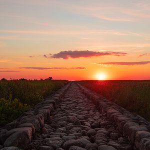 Preview wallpaper road, distance, sunset, stones, grass