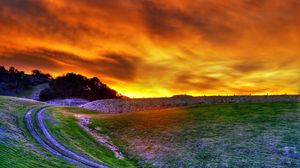 Preview wallpaper road, field, flowers, sky, decline, evening, orange, clouds