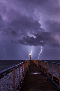 Preview wallpaper road, lighthouse, lightning, sea, dark, clouds