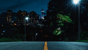 Preview wallpaper road, strip, lights, rays, trees, city, buildings