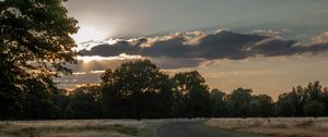 Preview wallpaper road, sunset, trees, clouds, sky, sun, rays