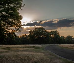 Preview wallpaper road, sunset, trees, clouds, sky, sun, rays