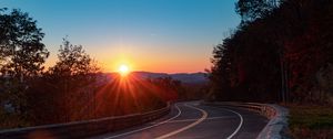 Preview wallpaper road, turn, trees, rays, sunset