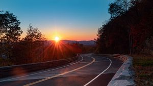 Preview wallpaper road, turn, trees, rays, sunset