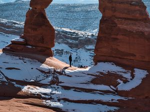 Preview wallpaper rock, arch, man, alone, snow, nature