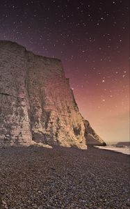 Preview wallpaper rock, cliff, coast, starry sky, pebble