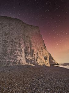 Preview wallpaper rock, cliff, coast, starry sky, pebble