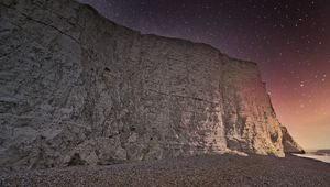 Preview wallpaper rock, cliff, coast, starry sky, pebble