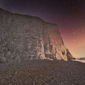 Preview wallpaper rock, cliff, coast, starry sky, pebble