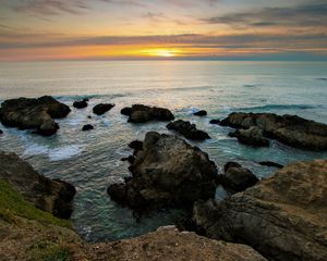 Preview wallpaper rocks, reeves, coast, sea, horizon, sun, evening, decline, emptiness, sky, grass, look, landscape