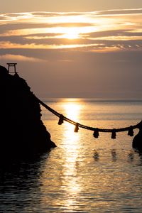 Preview wallpaper rocks, rope, sea, sun, sunset, dark