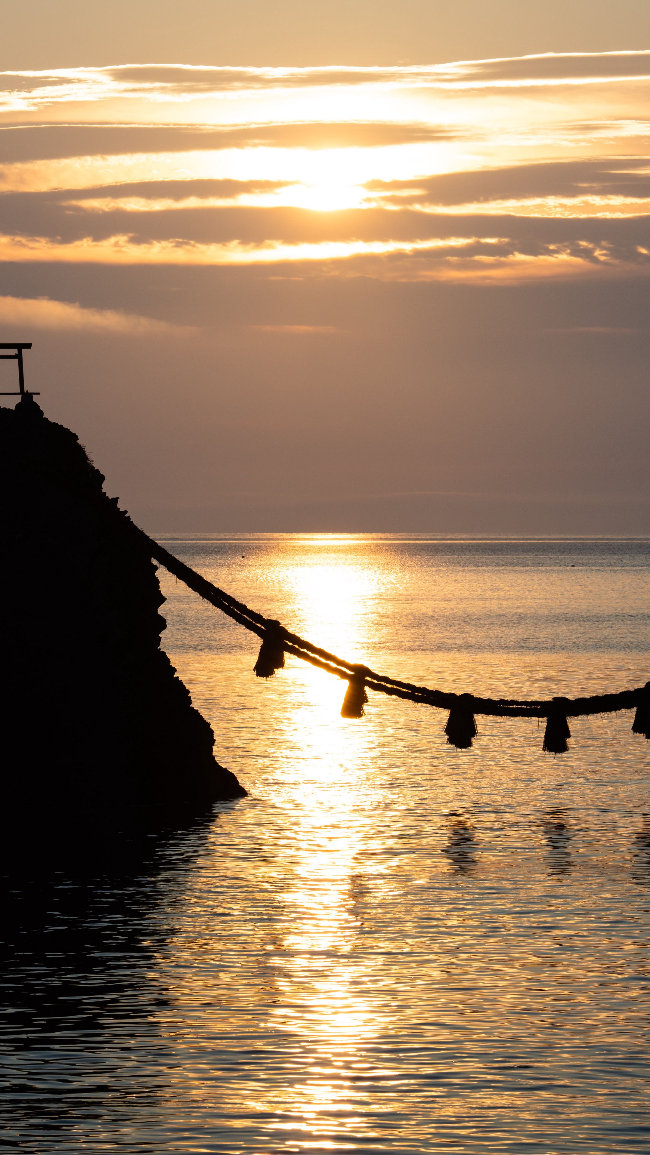 2160x3840 Wallpaper rocks, rope, sea, sun, sunset, dark