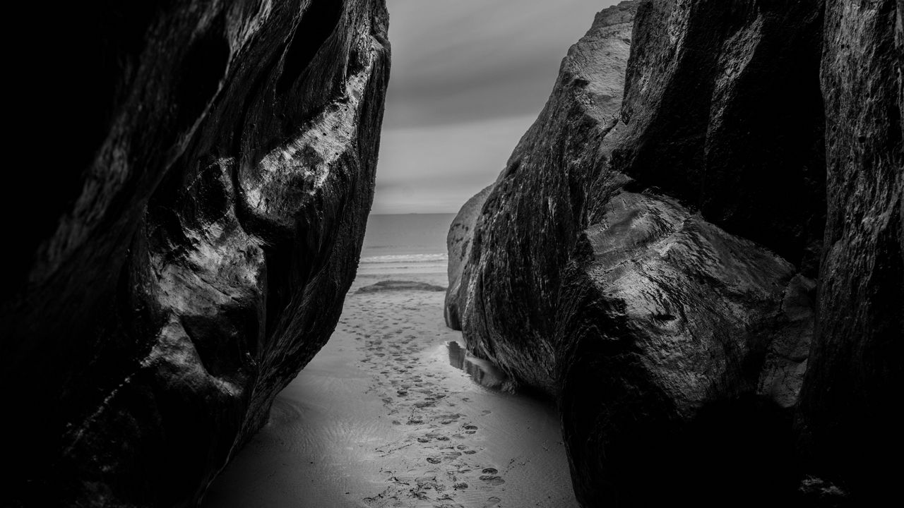 Wallpaper rocks, sand, footprints, sea, black and white