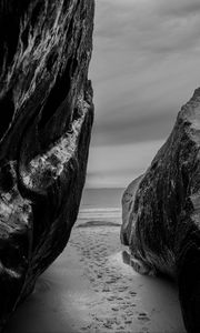 Preview wallpaper rocks, sand, footprints, sea, black and white