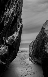 Preview wallpaper rocks, sand, footprints, sea, black and white