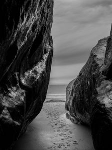 Preview wallpaper rocks, sand, footprints, sea, black and white